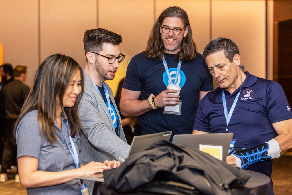 Group of professionals collaborating at a tech conference, focused on laptops and discussion | Services |