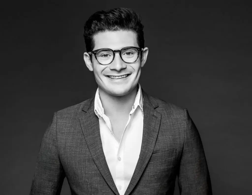 Smiling Man in Round Glasses and a Blazer Posing for a Studio Portrait