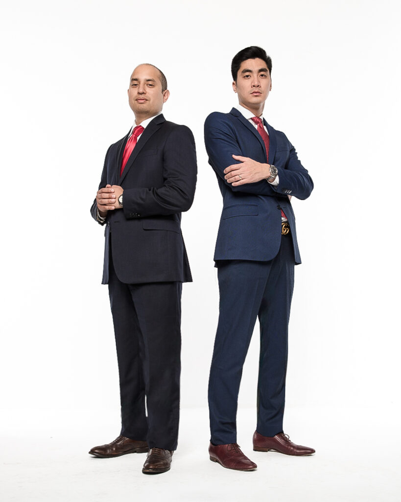 Two Businessmen in Suits Stand Back to Back with Arms Crossed Posing Confidently Against a White Background One in Navy and One in Black